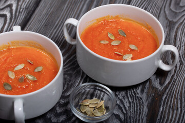 Pumpkin tomato cream soup. With the addition of pumpkin seeds. On pine boards.