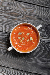 Pumpkin tomato cream soup. With the addition of pumpkin seeds. View from above. On pine boards.