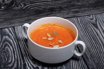 Pumpkin tomato cream soup. With the addition of pumpkin seeds. On pine boards.