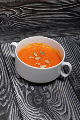 Pumpkin tomato cream soup. With the addition of pumpkin seeds. On pine boards.