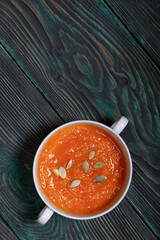Pumpkin tomato cream soup. With the addition of pumpkin seeds. View from above. On pine boards.