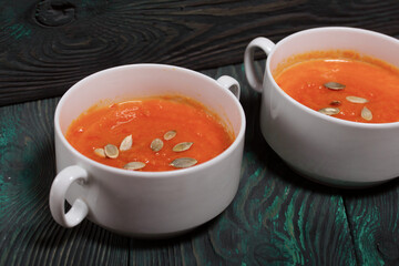 Pumpkin tomato cream soup. With the addition of pumpkin seeds. On pine boards.