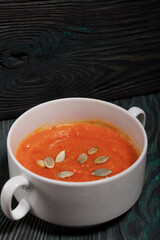 Pumpkin tomato cream soup. With the addition of pumpkin seeds. On pine boards.