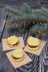 Eclairs with chocolate cream. Nearby is a spruce branch. On pine boards.