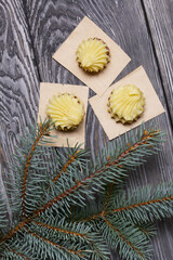Eclairs with chocolate cream. Nearby is a spruce branch. On pine boards.