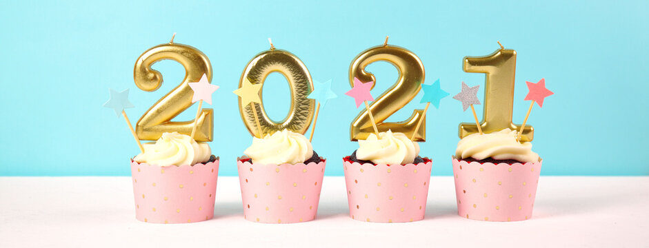 2021 Happy New Year's Eve pastel pink and blue theme cupcakes with large gold candles. Web banner sizing.