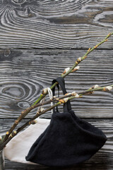 Blossoming willow branches. They are wearing medical masks. Against the background of pine boards.