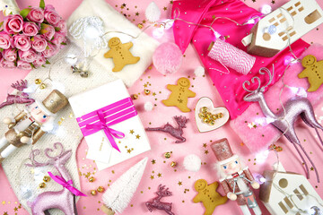 Modern Christmas morning popular social media style femine pink theme setting with gifts, ornaments, santa hat, and christmas stocking. Top view blog hero header creative composition flat lay.