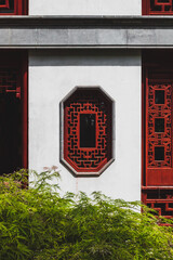 Red octagonal window on white wall of traditional house