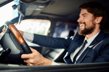 bearded man sitting in car salon in suit success trip lifestyle