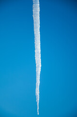 Naklejka na ściany i meble Frozen icicle isolated on a blue sky background.