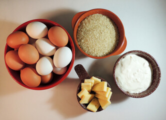 Red and brown clay bowls with rice, cheese, eggs and sour cream