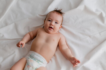 Baby boy 4 months lies on the bed with a white sheet, the view from above. space for text.