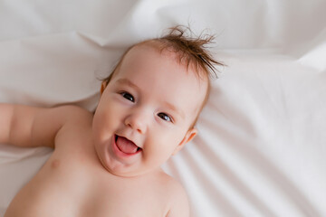 Baby boy 4 months lies on the bed with a white sheet, the view from above. space for text.