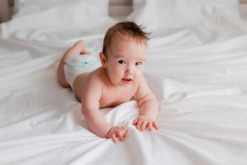 Toddler boy 4 months lies on the bed with a white sheet, space for text
