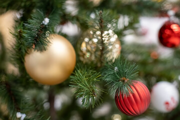 close-up Beautiful green Christmas tree branch decorated with toys balls of gold and red, soft focus, background snow in blur