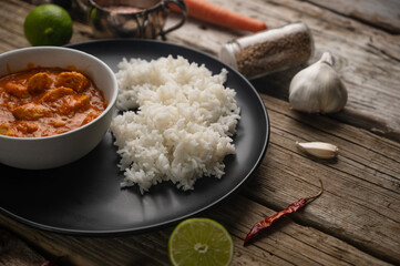 Macro shot view of hot chicken curry with boiled rice on rustic wooden table with spices background. Dinner with traditional Indian dish. Exotic delicious. Food concept. Restaurant menu. Cookbook.