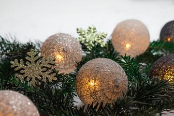 Obraz na płótnie Canvas Christmas composition with glowing baubles and shiny snowflakes lying on spruce branches. white background whith empty space
