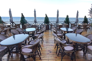 Seaview Restaurant Summer Terrace. Alfresco Sea Front Cafe With Wicker Rattan Furniture. Empty Seaside Patio Or Sundeck With Furniture.