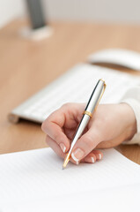 Close-up shot of a woman's hand writing her schedule on the notebook