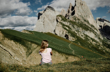 the girl sits on the edge of the cliff and looks at the opening beautiful view of the mountains. Dolomites. A man on top of a mountain looks at a magnificent landscape