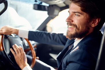 Cheerful business man in a suit driving a car trip passenger road