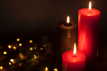 Lighted candles. Defocused Lights garlands in the background. On a dark background. Christmas card.