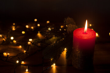 Lighted candles. Defocused Lights garlands in the background. On a dark background. Christmas card.