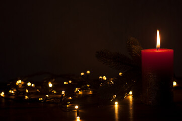 Burning candles in the dark. On a black background. Christmas. Garland light. Defocused background.