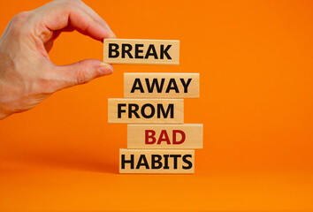 Time to break bad habits. Wooden blocks with words 'break away from bad habits'. Male hand. Beautiful orange background, copy space. Business and psychological concept.