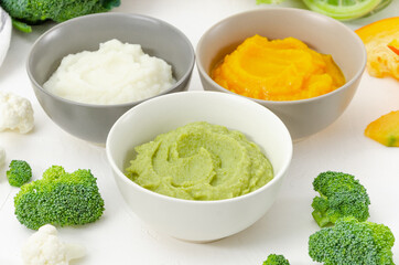 Baby food. Variation of the three homemade vegetable puree in bowls. Pumpkin puree, cauliflower puree and broccoli puree on a white background.