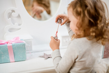 Shiny lip gloss in the hands of girl sitting in front of the mirror