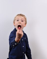 little boy with white hair and a navy blue shirt shakes his fist