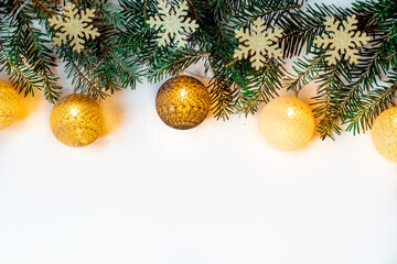 Fototapeta na wymiar Branches of spruce with glowing baubles lying on the Christmas background. White background with shiny snowflakes.