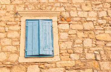 Fototapeta na wymiar Window with blue shutters on a stone building