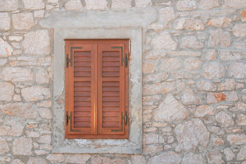 one window with brown closed and shutters, stone house