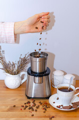 Electric coffee grinder grinding coffee beans and standing on the kitchen table, a Cup of black...