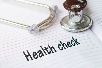 HEALTH CHECK. Text on a medical card next to a pen stethoscope. Medical concept.