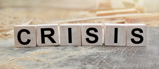 The word CRISIS is written on wooden cubes. Wooden cubes in the open air, overlooking the countryside. For business related design. Marketing concept.