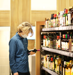 Supermarket shopping, face mask and gloves,Young man shopping in supermarket, reading product information.