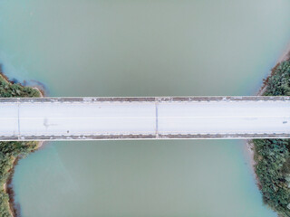 Top-down aerial view long white bridge. Aerial bird's eye view seascape and bridge background. Dirty river. Ecology problem