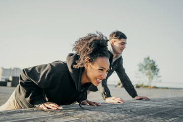 friends Man and woman African American in sports comfortable clothes for running aerobics fitness workout stretching on the waterfront in the city. A young couple playing sports on the street.