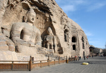 Yungang Grottoes near Datong in Shanxi Province, China. Cave 20, the most famous Buddha statues at Yungang. Wide view with unrecognizable people. Yungang Buddhist cave art UNESCO world heritage.