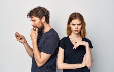 young couple in black t-shirts with phone communicating dissatisfaction lifestyle