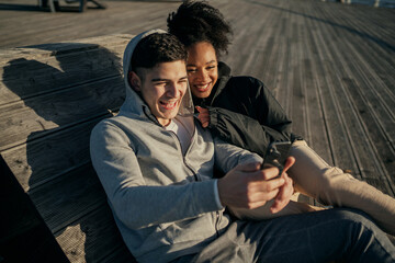 Fototapeta premium a couple of friends talk via video communication with friends via a social network, convenient use of modern technologies in communication. Walking on the street sitting on a bench nearby