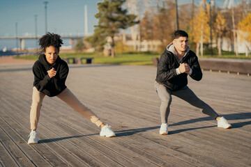 friends trainers muscle stretching Man and woman African American in sports comfortable clothing for aerobics fitness training on the waterfront in the city. couple playing sports in the Park