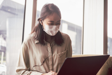 Asian woman with face mask working with notebook laptop in cafe. Concept for new normal and life in...