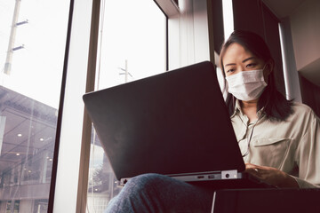 Asian woman with face mask working with notebook laptop in cafe. Concept for new normal and life in...