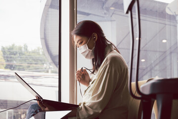 Asian woman with face mask working with notebook laptop in cafe. Concept for new normal and life in...