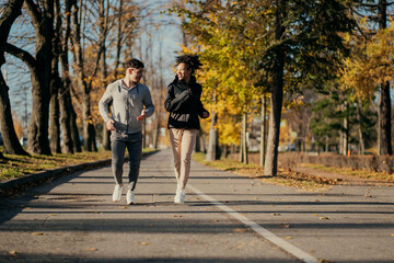 running in the Park friends trainers with each other. A man and an African American woman in sports comfortable clothing for aerobics fitness training in a Park in the city. the pair are engaged